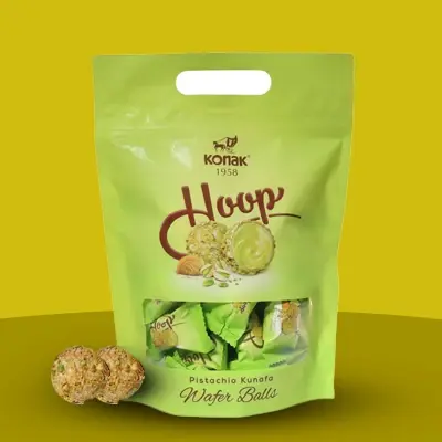 Konak Hoop Pistachio Kunafa Wafer Balls in a green resealable pouch with two unwrapped pieces displayed.