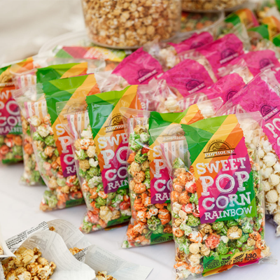 Multiple bags of Sweet Popcorn Rainbow displayed with vibrant, colorful caramel-coated popcorn.