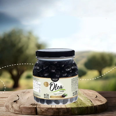 Olea black olives jar displayed on a rustic wooden surface with a lush olive grove in the background.