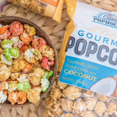 Bag of PopHouse Gourmet Caramelized Popcorn with Coconut alongside a bowl of colorful popcorn.